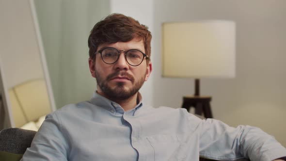 The Man Stares Intently at the Camera and Folds His Hands alt