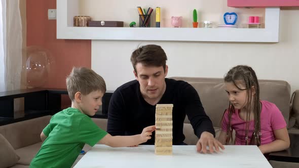 Older Brother Playing with Children in Jenga Board Game. Social Distancing and Self-isolation in