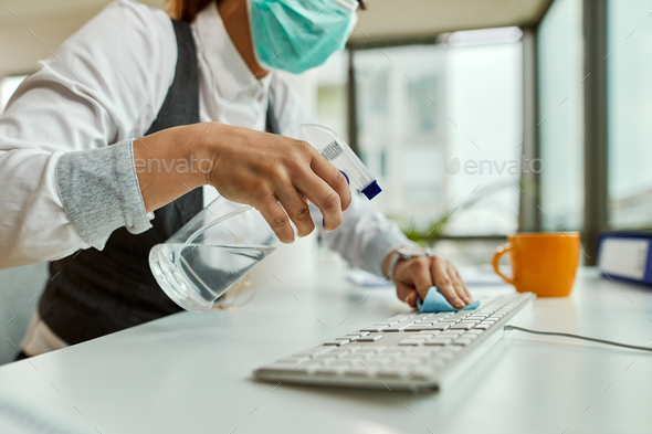 Close-up of businesswoman cleaning her computer keyboard in the office.