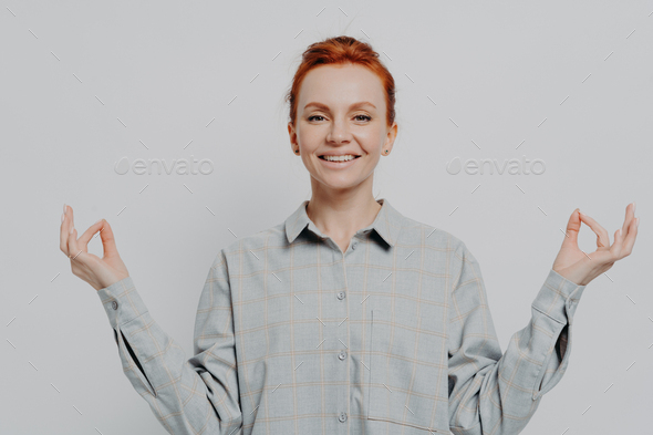 Peaceful young smiling redhead woman holding hands in mudra isolated on ...