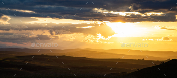 amazing sunset sky over green hills in early summer - Stock Photo - Images