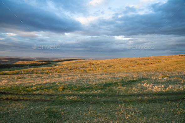 amazing sunset sky over green hills in early summer - Stock Photo - Images