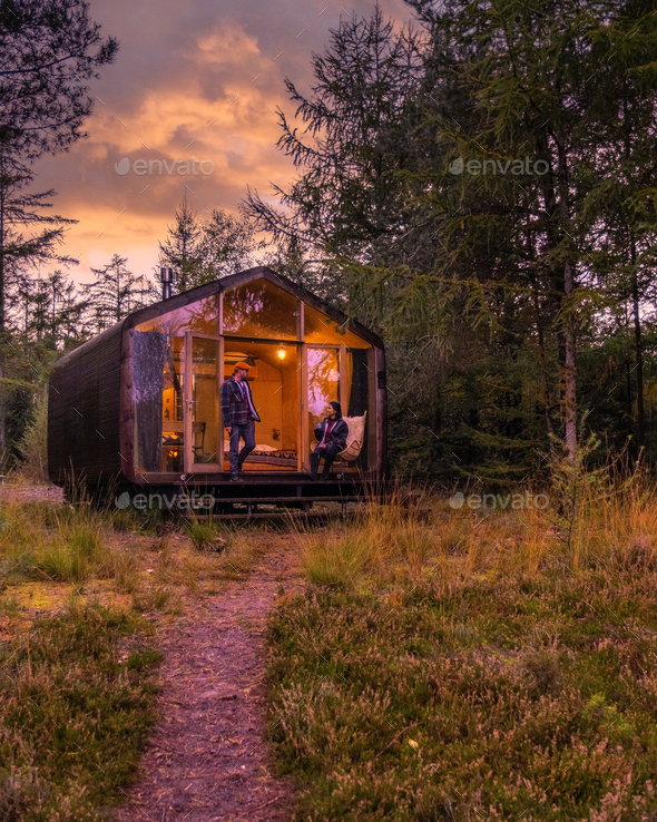 couple on a trip in the nature at a wooden hut in autumn forest in the Netherlands, cabin off grid