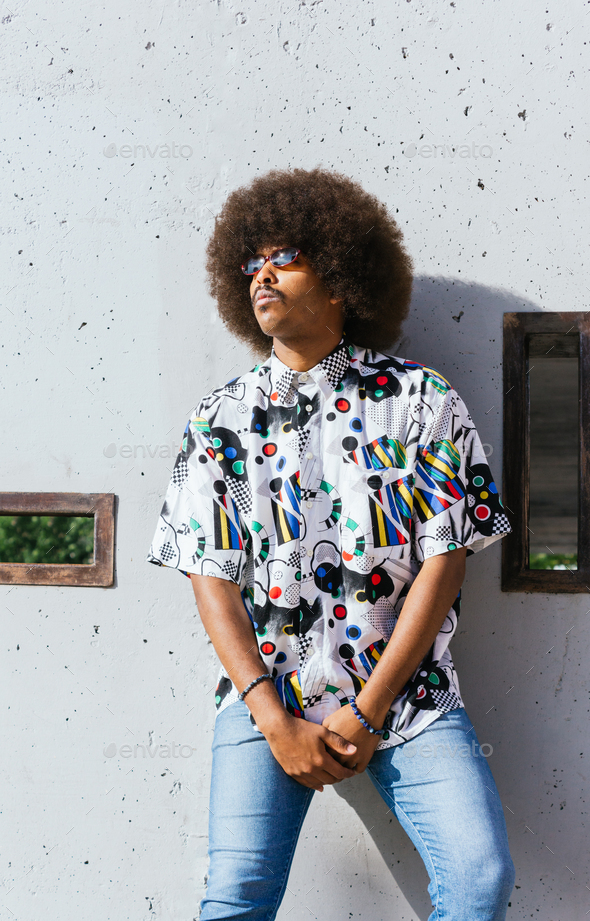 young black guy with afro hair standing leaning on a wall