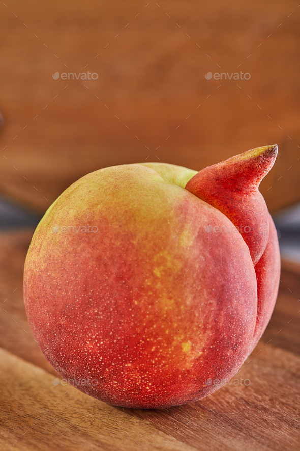 ugly fruit or vegetable. Heavily ugly peach mutant on a wooden background