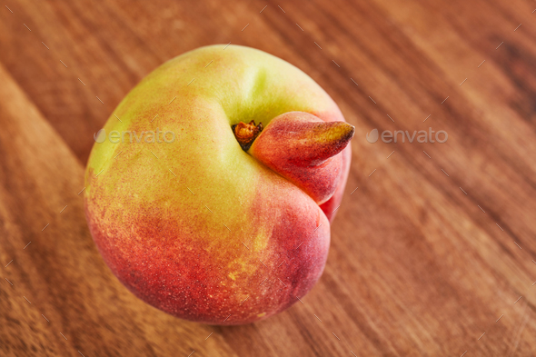 ugly fruit or vegetable. Heavily ugly peach mutant on a wooden background.