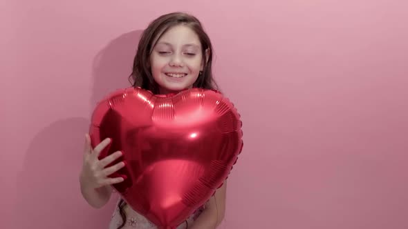 Beautiful Girl on a Pink Background with a Red Balloon in the Shape of a Heart alt