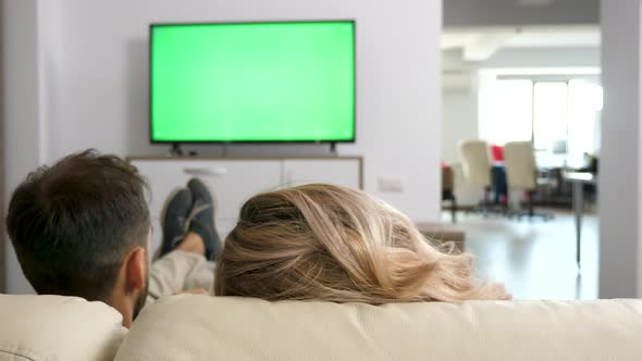 Man and Woman Cozy on the Couch Watch a TV with Green Screen alt