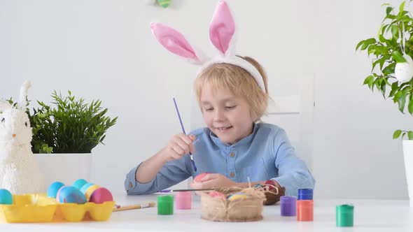 Cute boy coloring eggs for Easter holiday. Preparing for the holiday is a joy for kids.