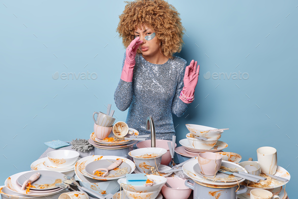 Displeased woman covers nose as feels unpleasant smell from dirty dishes wears silver dress and pink