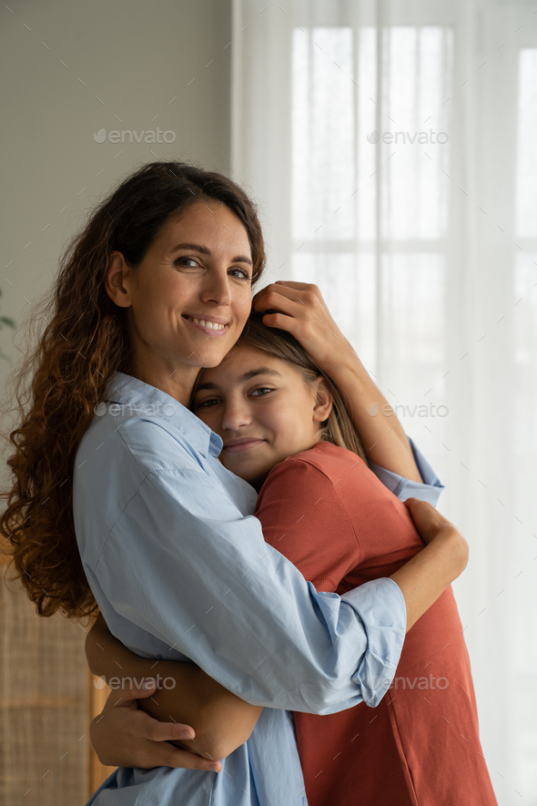 Happy mother and teenage girl daughter cuddling, hugging and smiling at ...