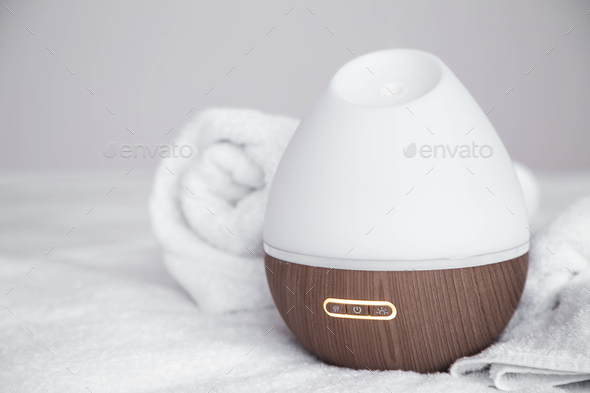 Spa composition with aroma diffuser and towel on a blurred background.