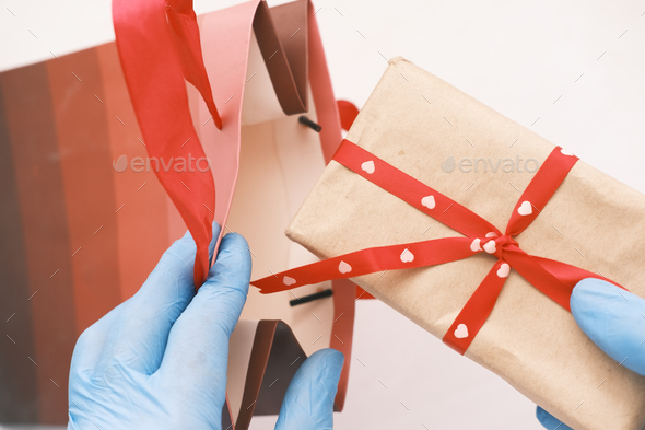 male hand in a blue medical glove putting a gift in a shopping bag
