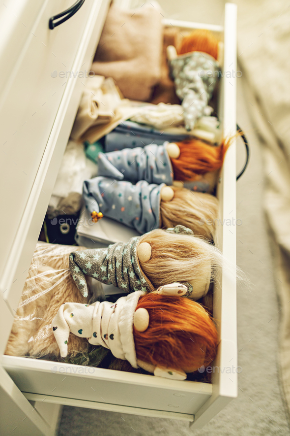 Bearded gnomes in caps lie in a chest of drawers. Handmade soft toy. Vertical shot. Soft focus
