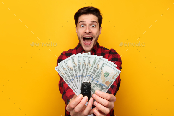 Excited Guy Showing Car Key And Money Cash, Yellow Background