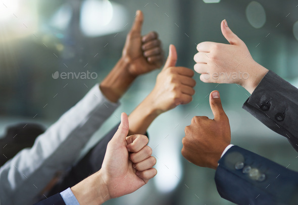 You did it. Shot of a group of office workers giving thumbs up together.