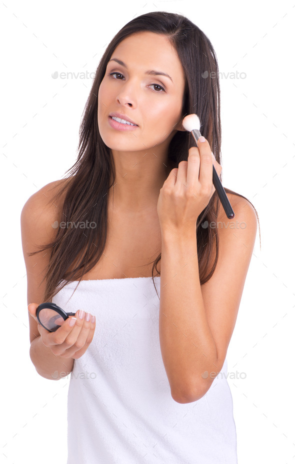 Adding color to her already radiant face. A young woman applying blush to her cheeks.