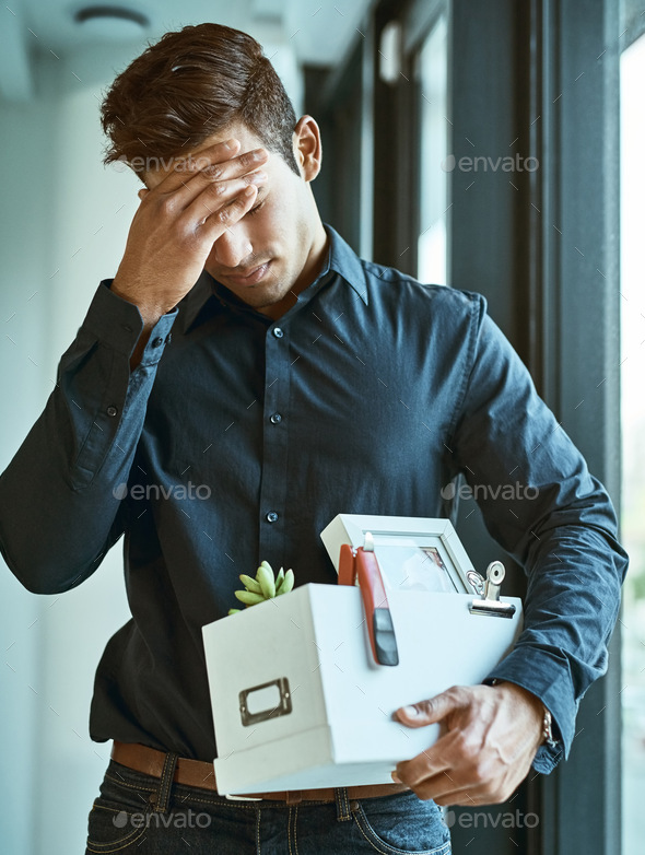 Shot of an unhappy businessman holding his box of belongings after getting fired from his job