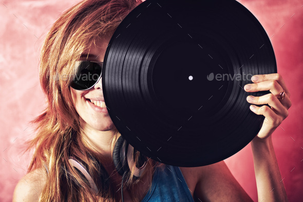 Fun portrait of a young woman holding a vinyl record up to her face