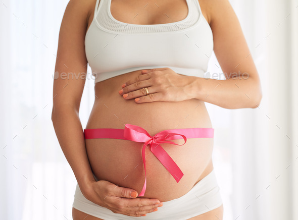 Cropped shot of a woman with a pink ribbon tied around her pregnant belly  Stock Photo by YuriArcursPeopleimages