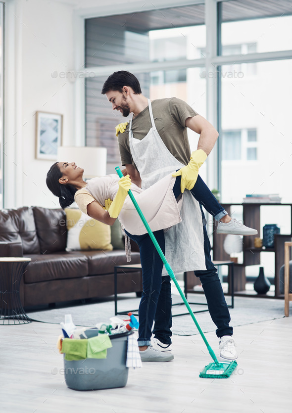 Romance changes everything. Shot of a happy young couple dancing while mopping the floor at home.