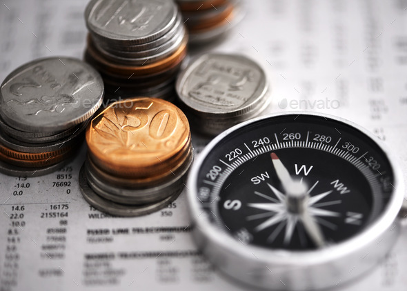 Leading the way to financial success. Studio shot of coins and a compass on some documents.