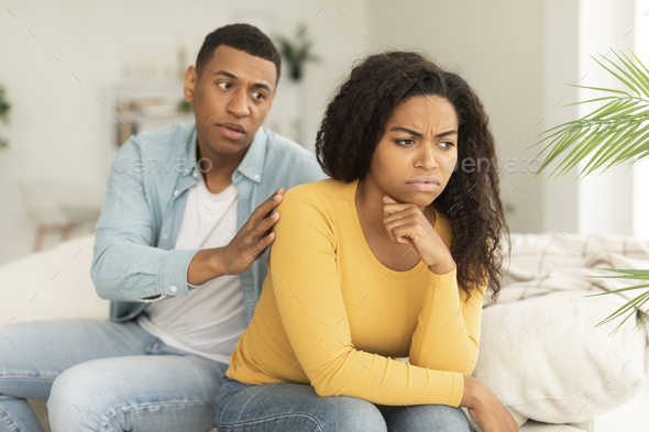Sad husband calms offended upset millennial african american wife, ignore guy after quarrel in