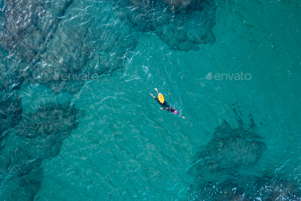 Aerial top view from drone of a swimmer in open water with wetsuit and buoy