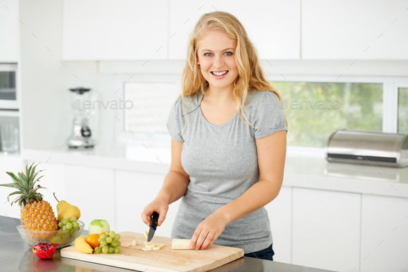 Nothing beats fresh fruit. Attractive curvaceous young woman chopping fruit in her kitchen.