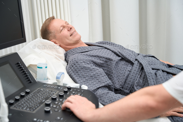 Middle-aged calm man lies on a couch in ultrasound room