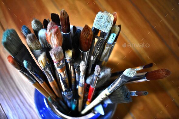 Closeup of the artist's paintbrushes in the blue vase. Stock Photo by  wirestock