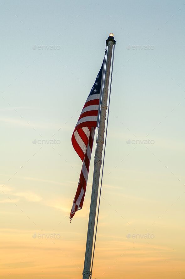 Vertical shot of American flag hanging from flag pole during sunset