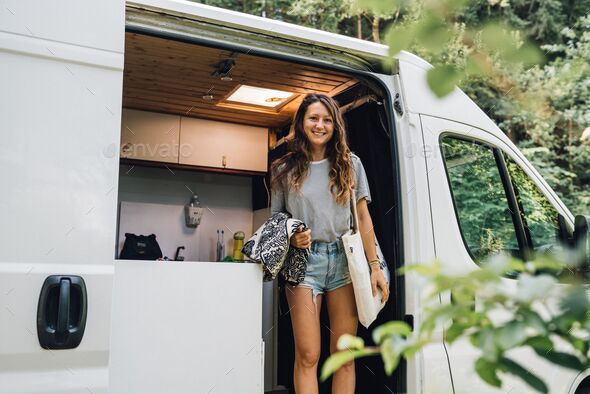 Beautiful Caucasian female in a van, smiling to the camera - van life concept