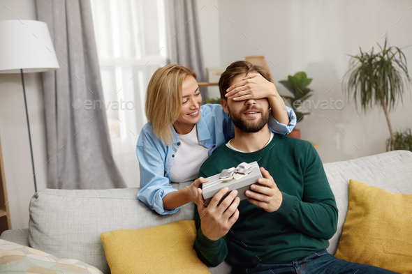 Happy Woman Presenting Gift To Husband. Woman Presenting Unexpected Present