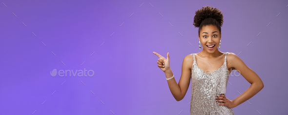 Smiling elegant african-american girl prom party wearing silver glittering evening dress pointing