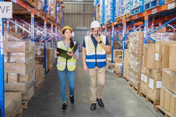 2 Staff in large depot storage warehouse manager and trainee walking ...