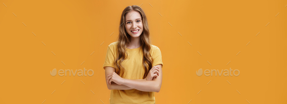 Portrait of kind and friendly charming young female student in casual t-shirt with wavy natural