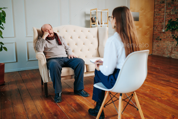 Worried sad senior man patient sitting at a psychologist\'s therapist appointment and telling