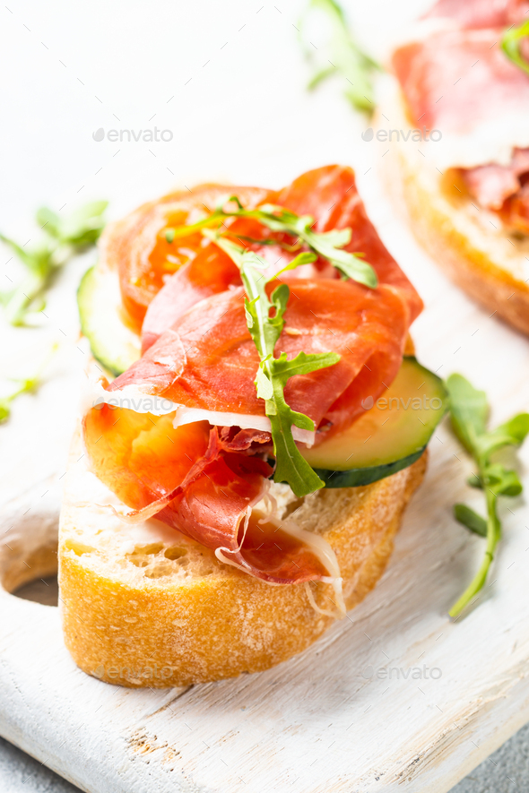 Open sandwiches with cream cheese, prosciutto, cucumber and arugula at