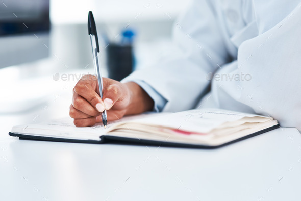 Noting down new findings. Closeup shot of an unrecognisable scientist writing notes in a lab.