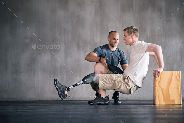 Hes getting better by the day. Shot of a physiotherapist helping a young male amputee workout.