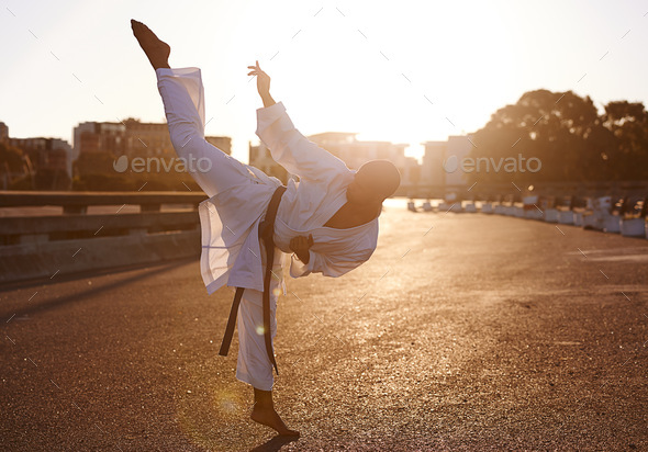 Hiiyah High kick. A young karate professional practicing while wearing a gi.