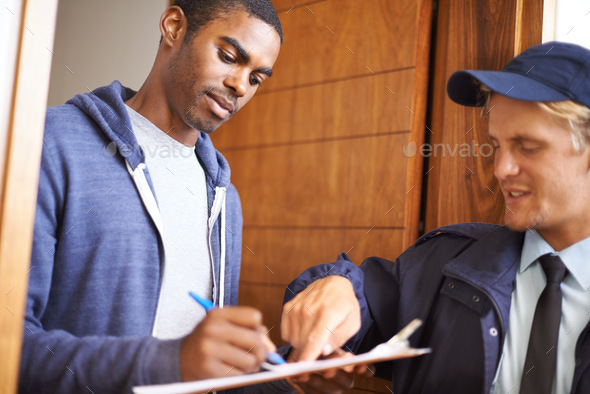 Put your name right here. Shot of a handsome young man signing a form for a courier.