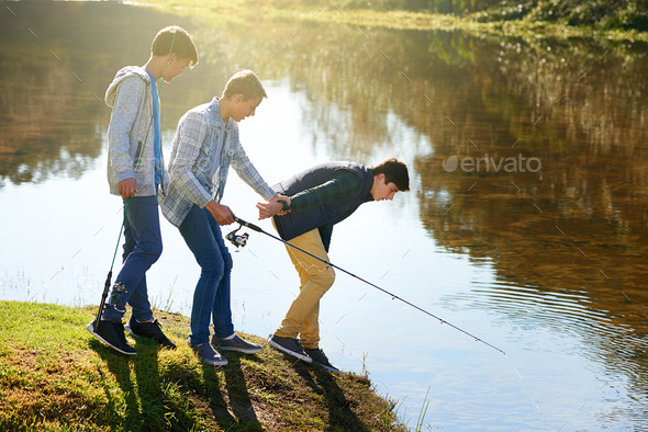 Let me have a lookShot of a group of young boys fishing by a lake. Stock  Photo by YuriArcursPeopleimages