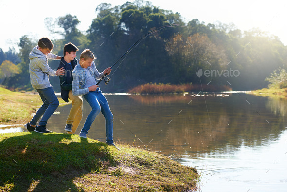 Its a big one. Shot of a group of young boys fishing by a lake