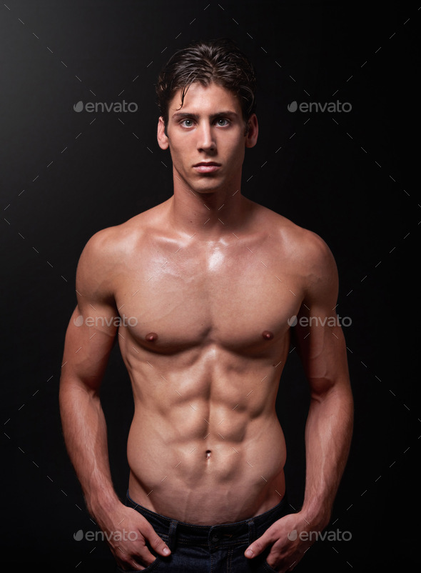 Studio shot of a handsome barechested young athlete standing against a black background Stock