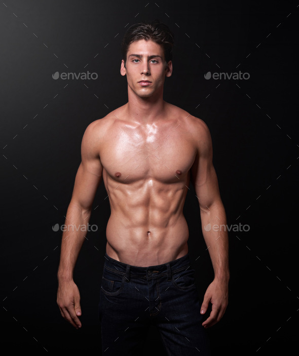 Studio shot of a handsome bare-chested young athlete standing against a ...