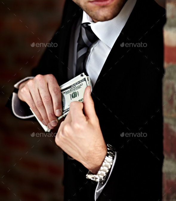 Hes got his payoff. Cropped shot of a man tucking a wad of cash into his jacket.