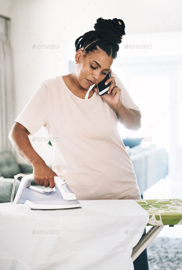 Multitasking is a skill. Shot of a young woman ironing clothes while on the phone at home.
