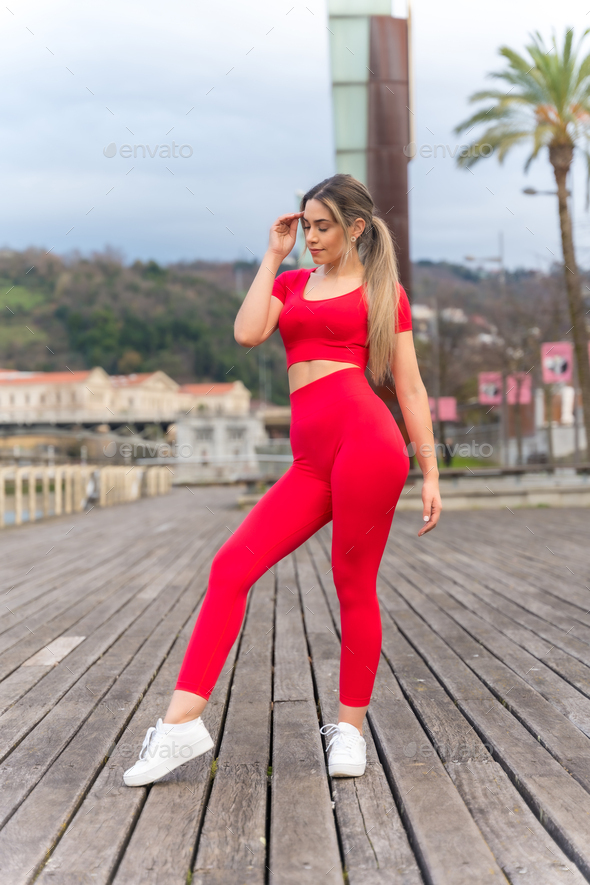 Portrait of fit woman in red clothes exercising in the city in spring, fitness